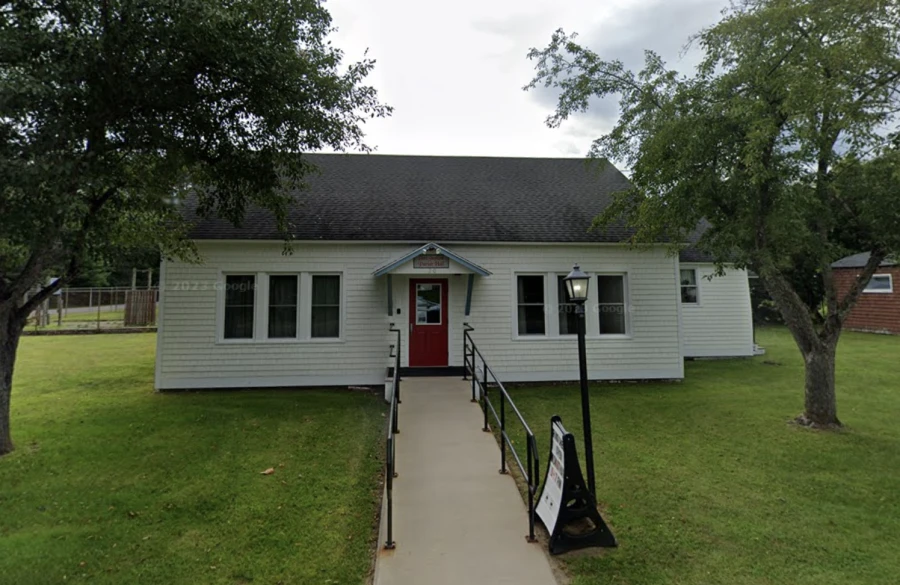 A simple, vinyl sided structure with concrete ramp to the red door